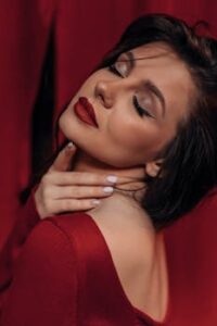 Elegant woman in a red dress embodies sophistication and sensuality with a graceful pose.